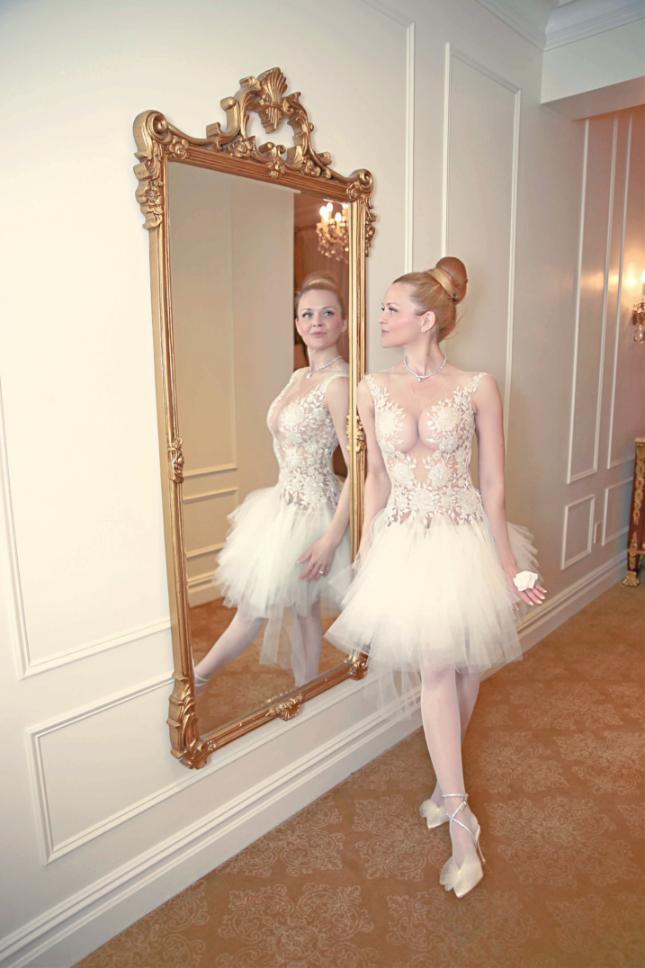 Charlotte in her ivory Reem Acra gown beside a gold mirror at The Plaza, from her original anniversary photographs