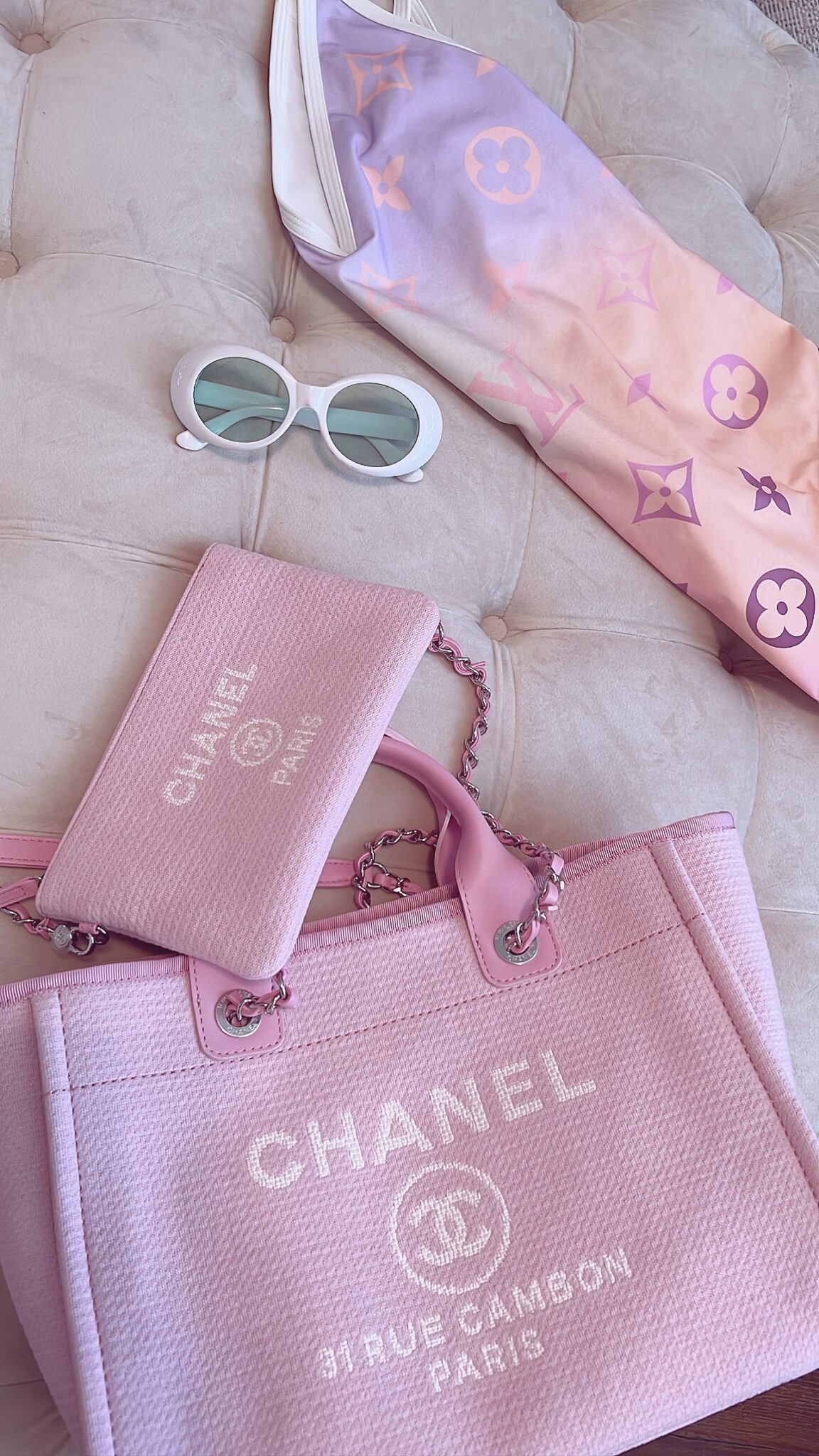 Pink Chanel tote and pouch, white oval sunglasses, and a pastel Louis Vuitton swimsuit