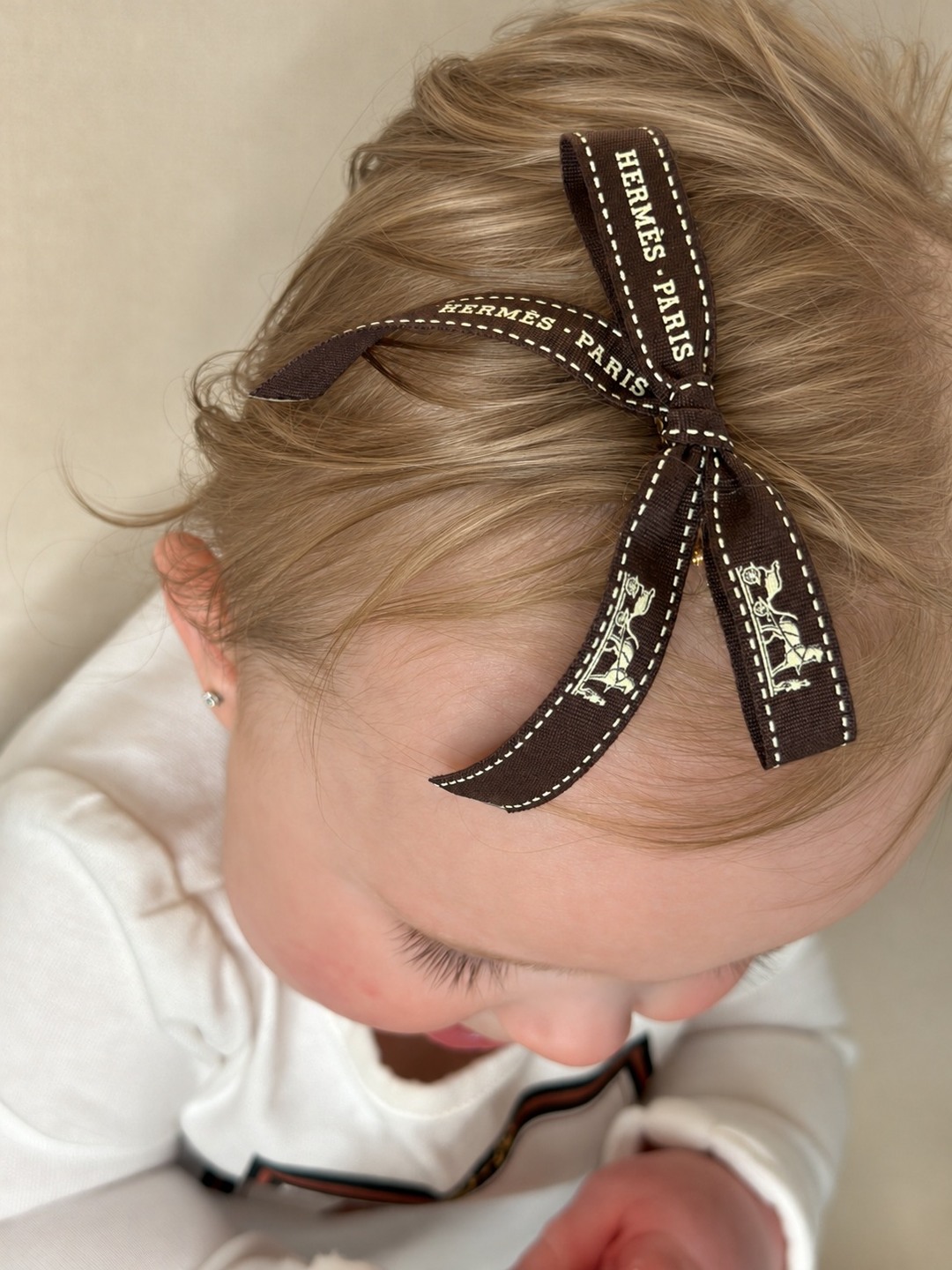 Madison’s dark blonde hair with a brown Hermès ribbon bow.