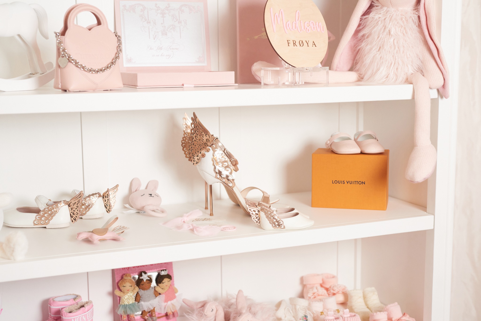 Madison’s white shelves displaying ivory butterfly baby shoes beside an adult butterfly heel, pink shoes, a pink bag, and soft toys.